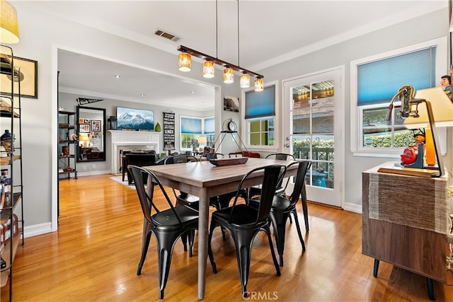 13611 Walnut St, Whittier, CA 90602 - dining room featuring a fireplace, light wood finished floors, baseboards, and crown molding