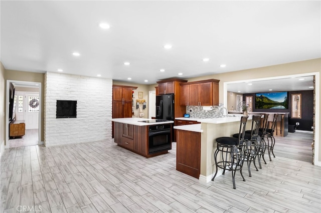 1325 N Birchnell Ave, San Dimas, CA 91773 - kitchen with black appliances, light wood-style flooring, light countertops, a kitchen breakfast bar, and recessed lighting