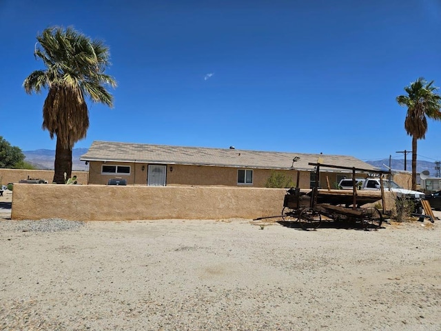 rear view of house with stucco siding and fence