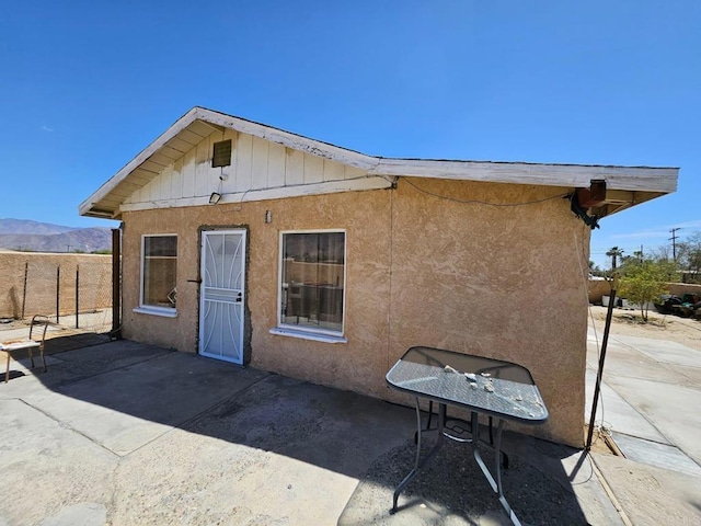 rear view of house with a patio area, fence, and stucco siding