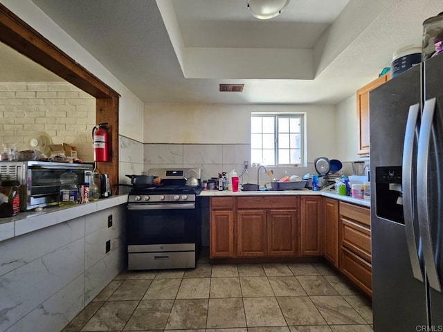kitchen with stainless steel appliances, a sink, light countertops, and a raised ceiling