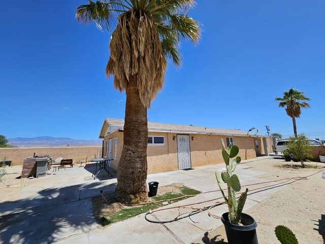 view of front of house featuring stucco siding, a patio area, and a mountain view