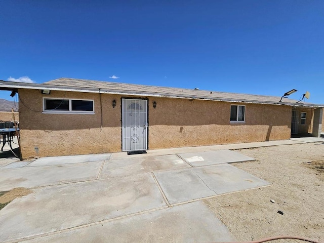 back of house with stucco siding and a patio area