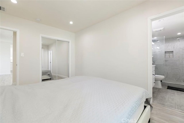 bedroom featuring recessed lighting, a closet, ensuite bath, and wood finished floors