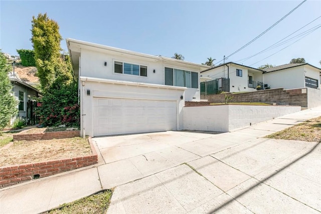view of front of house featuring stucco siding, driveway, a garage, and fence