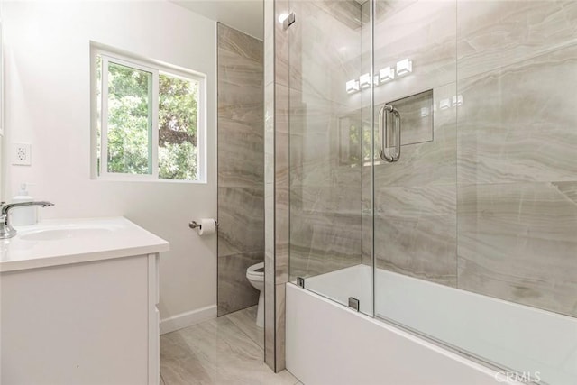 full bathroom with marble look tile flooring, toilet, vanity, shower / bath combination with glass door, and baseboards
