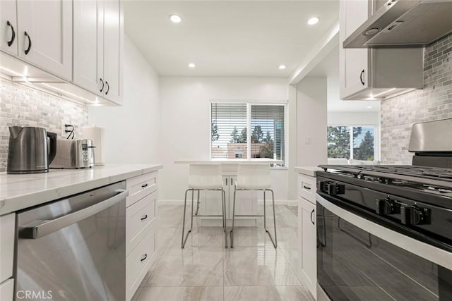 kitchen with stainless steel appliances, under cabinet range hood, light marble finish flooring, decorative backsplash, and recessed lighting