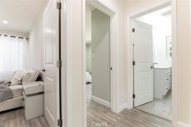 hall featuring light wood-type flooring, baseboards, and recessed lighting