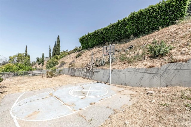 view of yard with fence and basketball hoop