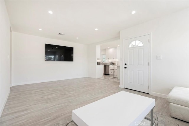 living area featuring light wood-style floors, baseboards, and recessed lighting