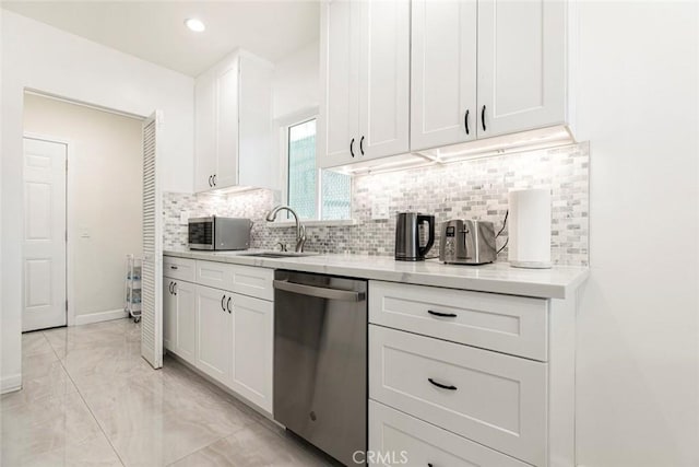 kitchen featuring appliances with stainless steel finishes, a sink, light marble finish floors, white cabinets, and decorative backsplash