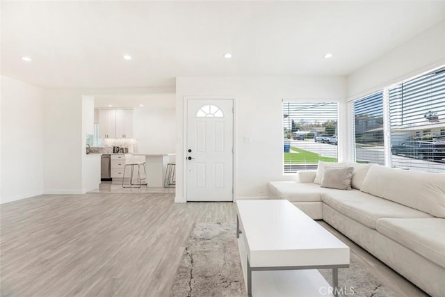living room featuring light wood-style flooring, baseboards, and recessed lighting