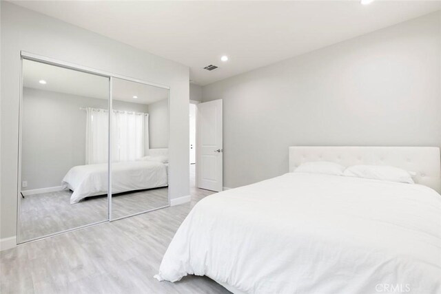 bedroom with wood finished floors, baseboards, recessed lighting, and a closet