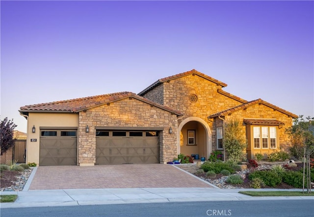 851 Trail View Pl, Nipomo, CA 93444 - mediterranean / spanish-style house with a garage, a tiled roof, decorative driveway, stone siding, and stucco siding