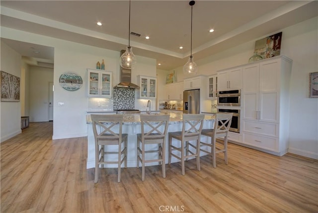 851 Trail View Pl, Nipomo, CA 93444 - kitchen with stainless steel appliances, wall chimney range hood, light wood finished floors, white cabinetry, and recessed lighting