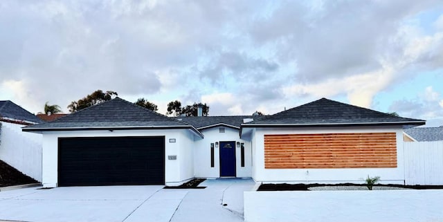 view of front facade featuring a garage, roof with shingles, concrete driveway, and stucco siding