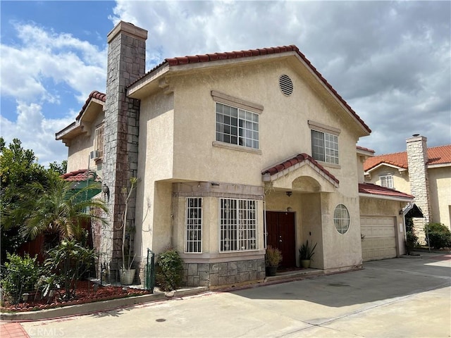 mediterranean / spanish house featuring driveway, stucco siding, a tiled roof, and a chimney