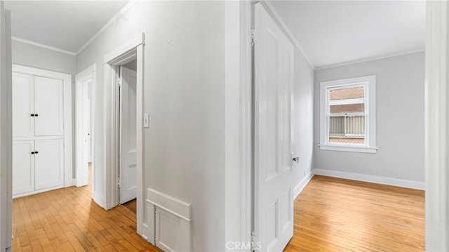 hallway with crown molding, light wood-type flooring, and baseboards