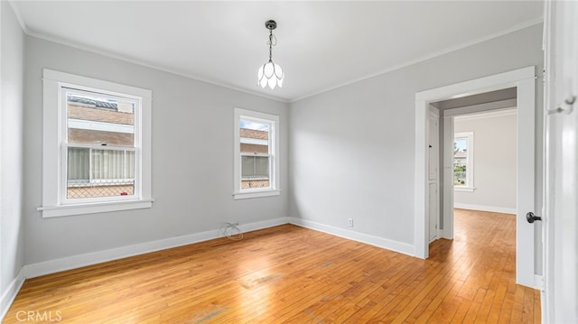 empty room with ornamental molding, light wood-type flooring, and baseboards