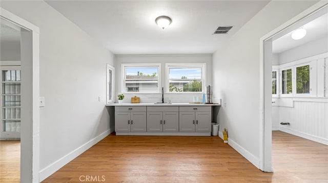 indoor wet bar featuring light wood-type flooring and baseboards