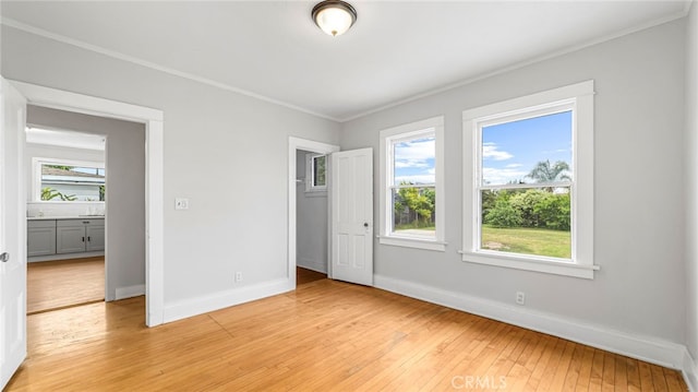 unfurnished bedroom featuring crown molding, light wood finished floors, baseboards, and a closet