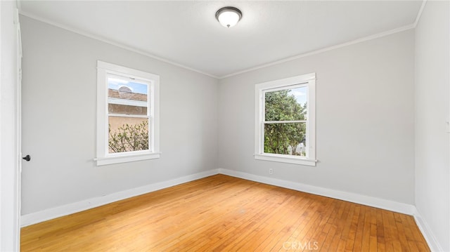 spare room with crown molding, light wood-style flooring, and baseboards