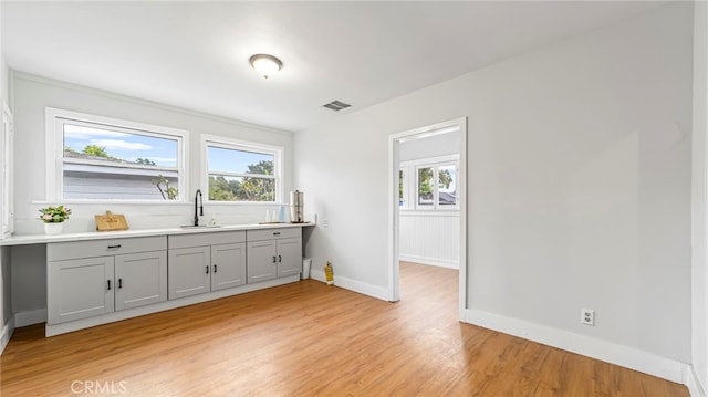 interior space with a sink, light wood finished floors, and baseboards