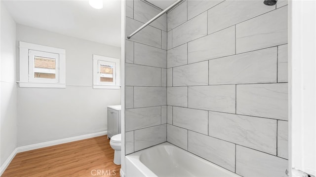 full bathroom with wood finished floors, baseboards, toilet, and shower / washtub combination