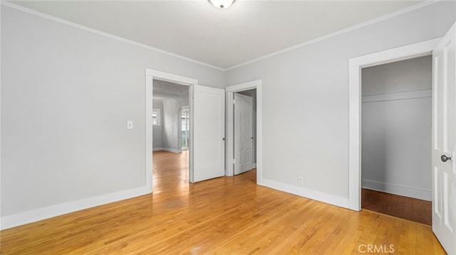 unfurnished bedroom with a closet, ornamental molding, light wood-style flooring, and baseboards