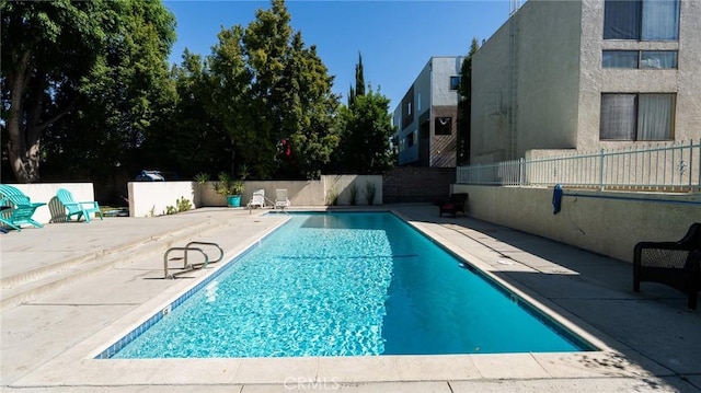 view of swimming pool with a patio and fence