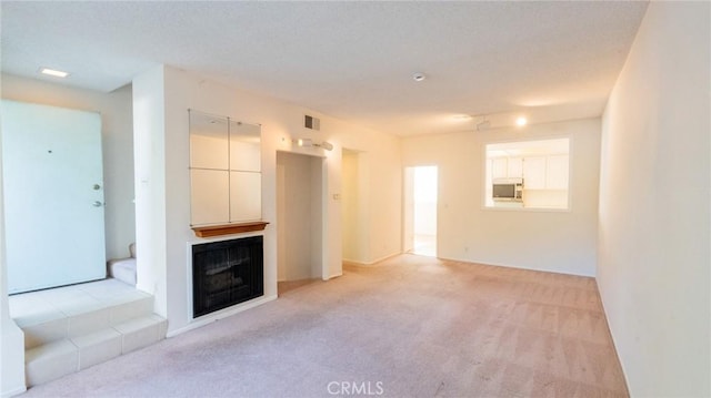 unfurnished living room featuring light colored carpet and a fireplace