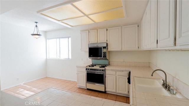 kitchen with range with gas cooktop, stainless steel microwave, tile countertops, a sink, and hanging light fixtures