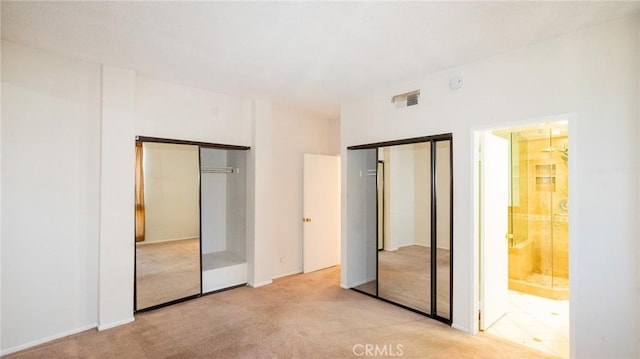 unfurnished bedroom featuring two closets and light carpet