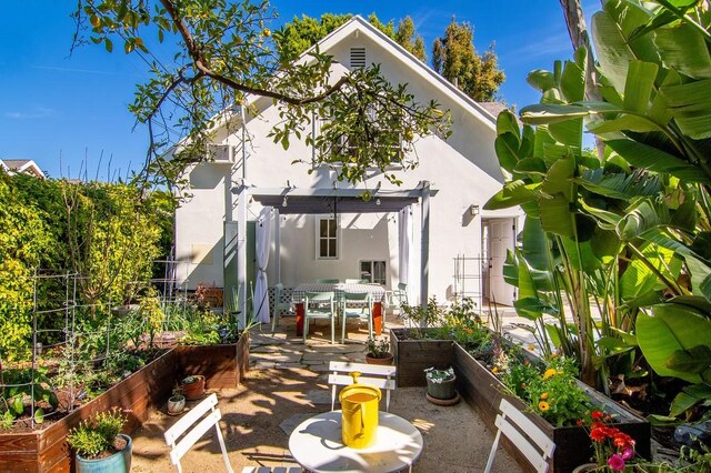 4001 Coldwater Canyon Ave, Studio City, CA 91604 - back of property featuring stucco siding, a vegetable garden, a patio area, and outdoor dining space