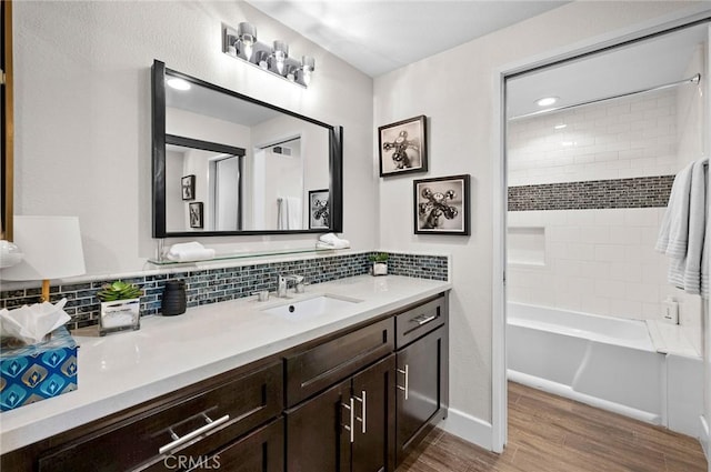 full bath featuring wood finished floors, backsplash, vanity, and shower / washtub combination