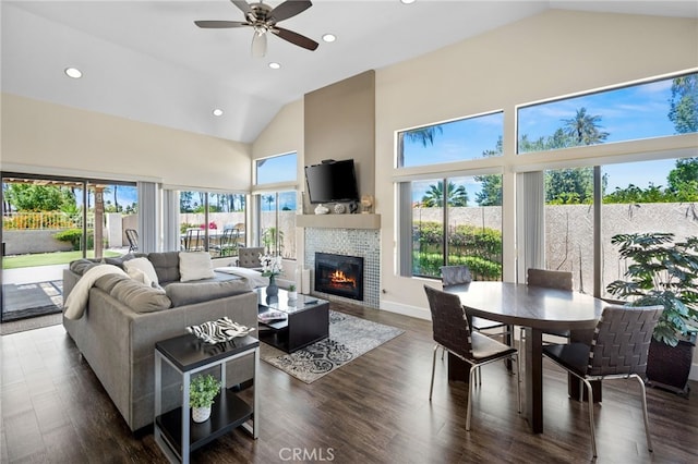 living area with high vaulted ceiling, ceiling fan, a glass covered fireplace, recessed lighting, and dark wood finished floors