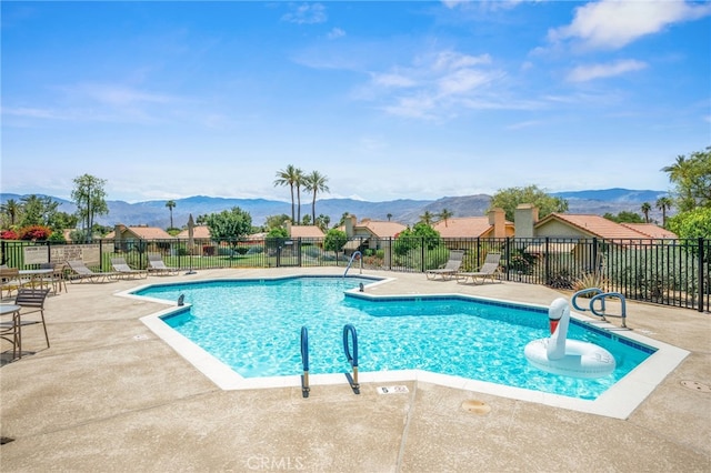 community pool with a mountain view, a patio, and fence