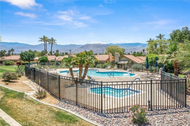 community pool with fence, a mountain view, and a patio