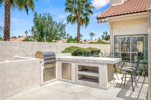 view of patio featuring a grill, exterior kitchen, and fence