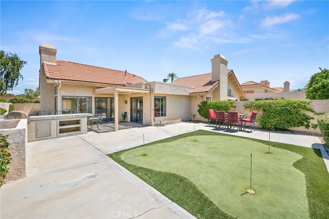 back of property with fence, a putting green, a tiled roof, and a patio