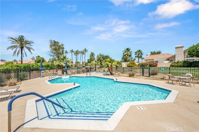 community pool with a patio area and fence