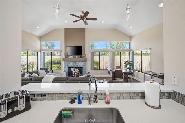 kitchen with high vaulted ceiling, a sink, a lit fireplace, a ceiling fan, and recessed lighting