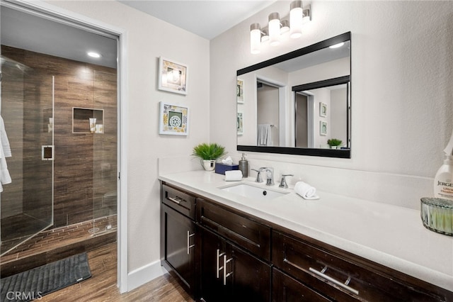 full bathroom featuring a stall shower, vanity, wood finished floors, and baseboards