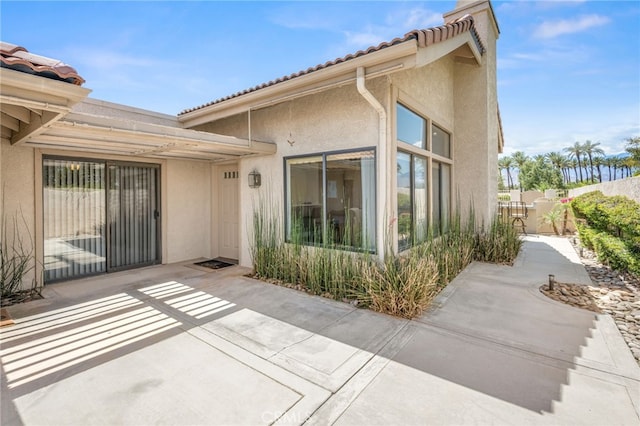 back of house featuring a patio, stucco siding, a tiled roof, fence, and a chimney