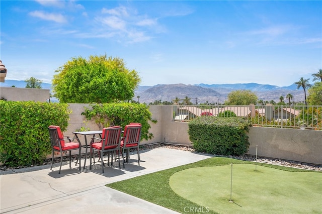 view of patio / terrace featuring a putting area, a fenced backyard, and a mountain view