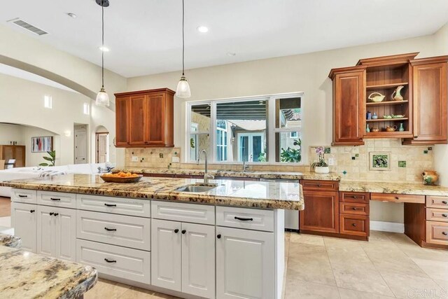 1455 Independence Way, Vista, CA 92084 - kitchen featuring a sink, arched walkways, backsplash, light stone countertops, and decorative light fixtures