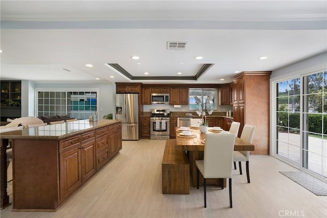 dining room featuring light wood-style flooring, ornamental molding, plenty of natural light, a raised ceiling, and recessed lighting