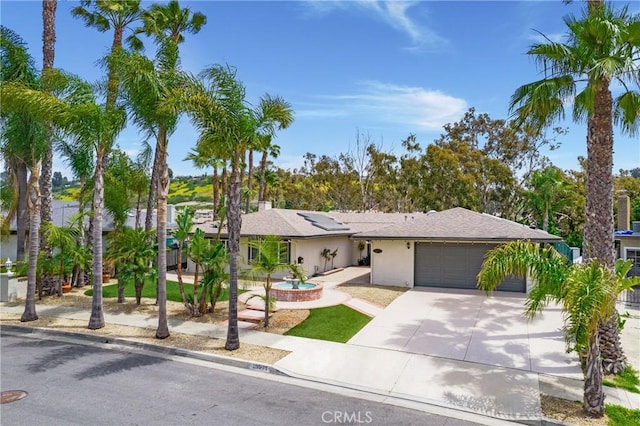ranch-style house with driveway, a garage, roof mounted solar panels, and stucco siding