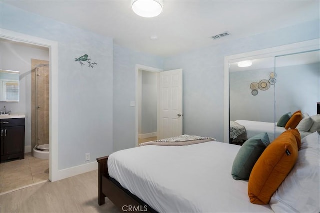 bedroom featuring a closet, baseboards, and ensuite bath