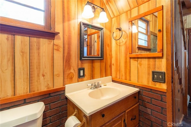26370 Alpine Ln, Twin Peaks, CA 92391 - bathroom featuring toilet, wooden walls, vanity, and brick wall